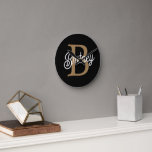 Modern Elegant Monogram Name  Black Gold Script  Round Clock<br><div class="desc">The Modern Elegant Monogram Name Black Gold Script Clock is a stylish and personalized timepiece perfect for any home or office setting. This clock features a sleek black face with elegant gold script, allowing you to customize it with your monogram and name. The modern design and sophisticated colour scheme make...</div>