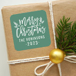 Modern Script Green Merry Christmas Custom Square Sticker<br><div class="desc">Stylish Merry Christmas holiday favour sticker features white script writing and accents of branches with holly leaves and berries. Personalize with custom name / family and year text. The green background colour can be modified.</div>