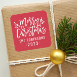 Modern Script Red Merry Christmas Custom Square Sticker<br><div class="desc">Stylish Merry Christmas holiday favour sticker features white script writing and accents of branches with holly leaves and berries. Personalize with custom name / family and year text. The crimson red background colour can be modified.</div>