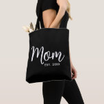 Mom Established Date White Script New Mom Gift Tote Bag<br><div class="desc">Being a mom is one of the most important jobs in the world. Show your favourite mom that you care with this custom, minimal tote bag. Simple white script calligraphy and white sans serif typography overlay a black tote bag. Personalize with the mom “established” year date when your first child...</div>