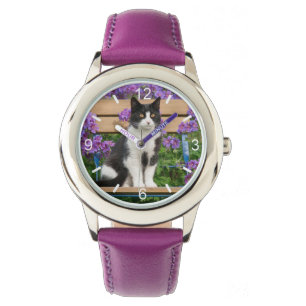 Montre Le chat de Tuxedo assis sur une chaise de jardin a