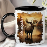Moose in Misty Lake Reflection Mug<br><div class="desc">Savour your favourite beverage with the Moose in Misty Lake Reflection Mug. This captivating mug features a majestic moose standing in a misty lake, with the soft, golden hues of dawn and the tranquil forest beautifully reflected in the water. Customized with your name, it adds a personal and unique touch....</div>