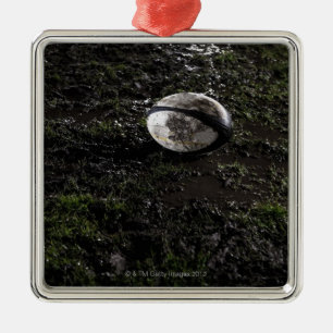 Muddy rugby ball sitting on a chewed up grass metal ornament