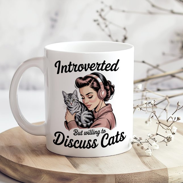 Mug "Introverted But Willing to Discuss Cats" Funny ("Introverted But Willing to Discuss Cats" Funny Coffee Mug on a sunny boho kitchen table.)
