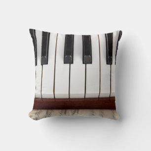 musical notes on the background of a pianoacoustic throw pillow