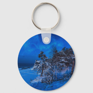 Nighttime winter scene with snow covered pines keychain