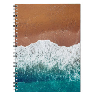 Ocean wave on a sandy beach, background  top view  notebook