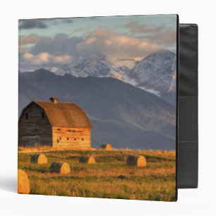 Old barn framed by hay bales and dramatic binder