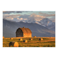Old barn framed by hay bales and dramatic
