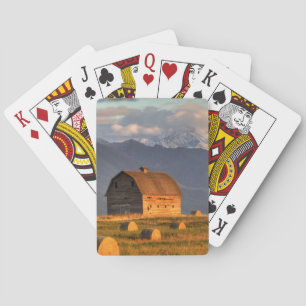 Old barn framed by hay bales and dramatic playing cards