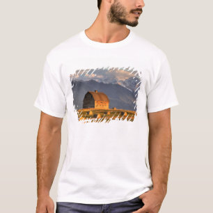 Old barn framed by hay bales and dramatic T-Shirt