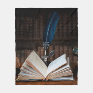 Old books, quill pen and vintage inkwell on wooden fleece blanket