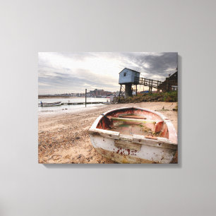 Old red rowing boat on the beach with tower canvas print