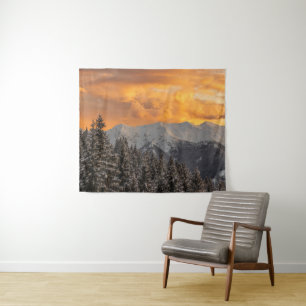Orange clouds above mountains and spruce forest tapestry