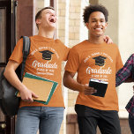 Orange White Graduate Custom Graduation T-Shirt<br><div class="desc">This orange custom senior graduate t-shirt features classy white typography of your high school or college name for the class of 2025. Customize with your graduating year under the chic white handwritten script and black grad cap for a great personalized graduation tee for a party or keepsake gift for your...</div>