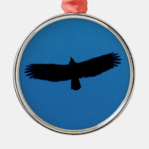Ornement Métallique Un oiseau noir dans un ciel bleu