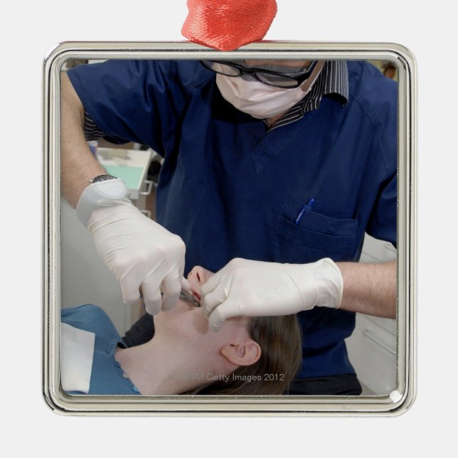 Orthodontist readjusting the dental braces of a metal ornament (Front)