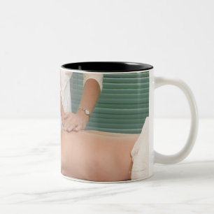 Osteopath/chiropractor manipulating back Two-Tone coffee mug