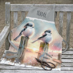 Pastel Watercolor Birds Fencepost Sunset Apron<br><div class="desc">Soft watercolor brushwork captures two fluffy songbirds resting on weathered fence posts as a glowing sunset spreads across a dreamy countryside sky. Gentle washes of peach, blush pink, pale blue, and warm gold blend into a tranquil horizon, creating a calm pastoral atmosphere. The birds appear round and feathery, their delicate...</div>