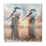 Pastel Watercolor Birds Fencepost Sunset Tile<br><div class="desc">Soft watercolor brushwork captures two fluffy songbirds resting on weathered fence posts as a glowing sunset spreads across a dreamy countryside sky. Gentle washes of peach, blush pink, pale blue, and warm gold blend into a tranquil horizon, creating a calm pastoral atmosphere. The birds appear round and feathery, their delicate...</div>