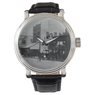 Pedestrians, cyclists, and horse-carriages watch
