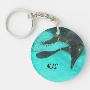 Penguin diving in blue water on a keychain