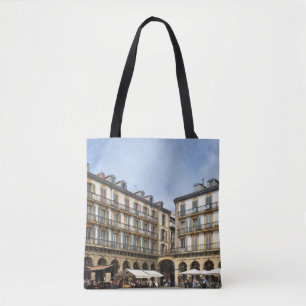 PEOPLE WALKING NEAR BEIGE CONCRETE BUILDING DURING TOTE BAG