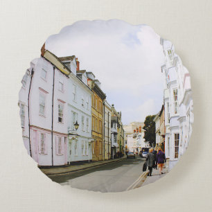 PEOPLE WALKING ON SIDEWALK BESIDE BUILDING AND ROA ROUND PILLOW