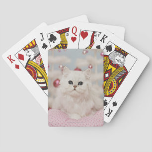 Persian cat sitting on pink pillow playing cards