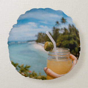Person holding mason jar with filled with juice at round pillow
