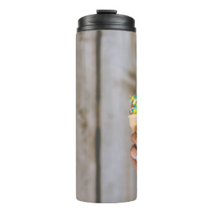 Person holding multicolored ice cream thermal tumbler