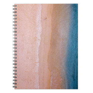 Person walking on sand near seashore leaving foot notebook