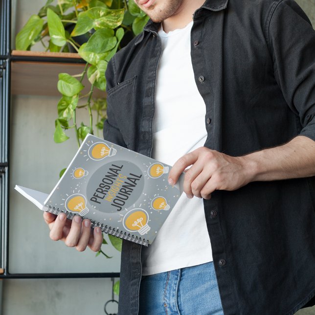 Personal Insights Journal Lightbulb Notebook (A man looking at his notebook which is entitled Personal Insights Journal, covered in lightbulbs)