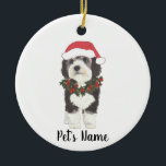 Personalized Bernedoodle Red and Green Christmas Ceramic Ornament<br><div class="desc">I am in love with this beautifully detailed watercolor illustration of a grey, black, and white bernedoodle or sheepadoodle on an ornament with a sweet santa hat and red and green holly wreath outfit! Personalize these pastel ornaments and make the nice list this year! For the perfect presents, pair it...</div>