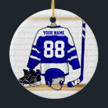 Personalized Blue and White Ice Hockey Jersey Ceramic Ornament<br><div class="desc">A personalized ice hockey jersey in blue and white hanging in a sports locker room with a helmet, ice skates and an ice hockey stick. The jersey can be fully customized with the number and name of your choice to make a great gift for the ice hockey fan, ice hockey...</div>