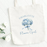 Personalized Blue Hydrangea Bow Floral Flower Girl Tote Bag<br><div class="desc">Delight your little flower girl with this beautiful personalized tote bag, featuring a soft dusty blue hydrangea bouquet design. Perfect for carrying essentials on the big day or as a cherished keepsake, this tote makes a sweet and thoughtful gift. The customizable name makes it a one-of-a-kind piece that she’ll treasure...</div>