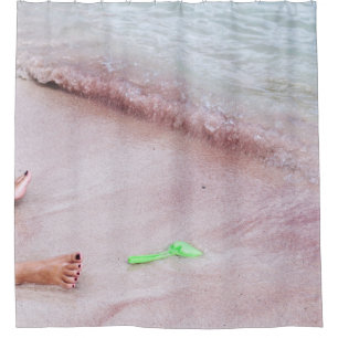 Person's foot beside green shovel on seashore