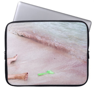 Person's foot beside green shovel on seashore laptop sleeve