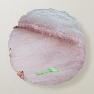 Person's foot beside green shovel on seashore round pillow
