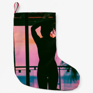Petite Chaussette De Noël Femme en débardeur noir et pantalon debout sur le