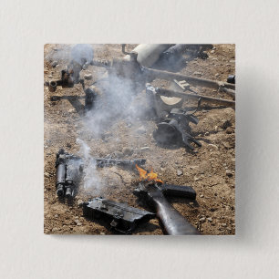 Pieces of enemy weapons lay out to cool off 2 inch square button