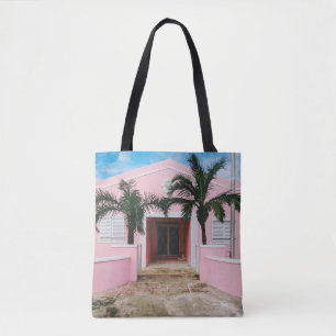 Pink and white concrete house near green trees und tote bag