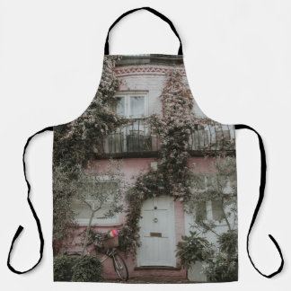 PINK AND WHITE PAINTED HOUSE COVERED WITH PLANTS A APRON
