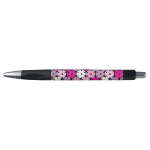 Pink, white and purple pickleballs, pen
