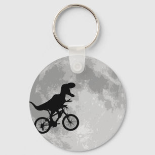 Porte-clés Dinosaure sur un vélo dans le ciel avec la lune
