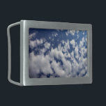 Puffy Clouds On Blue Sky Belt Buckle<br><div class="desc">A bank of puffy white clouds breaks into small wispy pieces across the frame of the vertical photograph. The cloud cover is denser on the left and more sparse on the right, revealing a deep blue sky that is dark near the top of the photo and lighter near the bottom....</div>