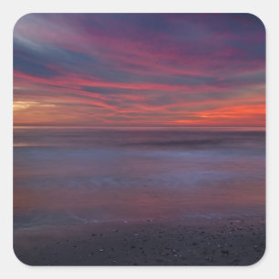 Purple-coloured sunrise on ocean shore square sticker
