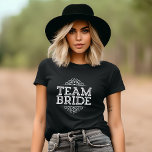Purple & White Cute Team Bride Wedding Party Gift T-Shirt<br><div class="desc">Cute Trendy Chic Girly Modern Elegant Typography Design Reads "Team Bride" with Fancy Scroll Frame Border. Perfect gift for bride, bridesmaids and wedding party to wear while getting ready on your wedding day! Click the "Customize It" button to personalize the front with your names or other custom text for a...</div>