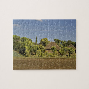 Puzzle Un champ cultivé devant des maisons à toit de chau
