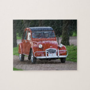 Puzzle Une vieille voiture rouge Citroen 2CV avec une fem
